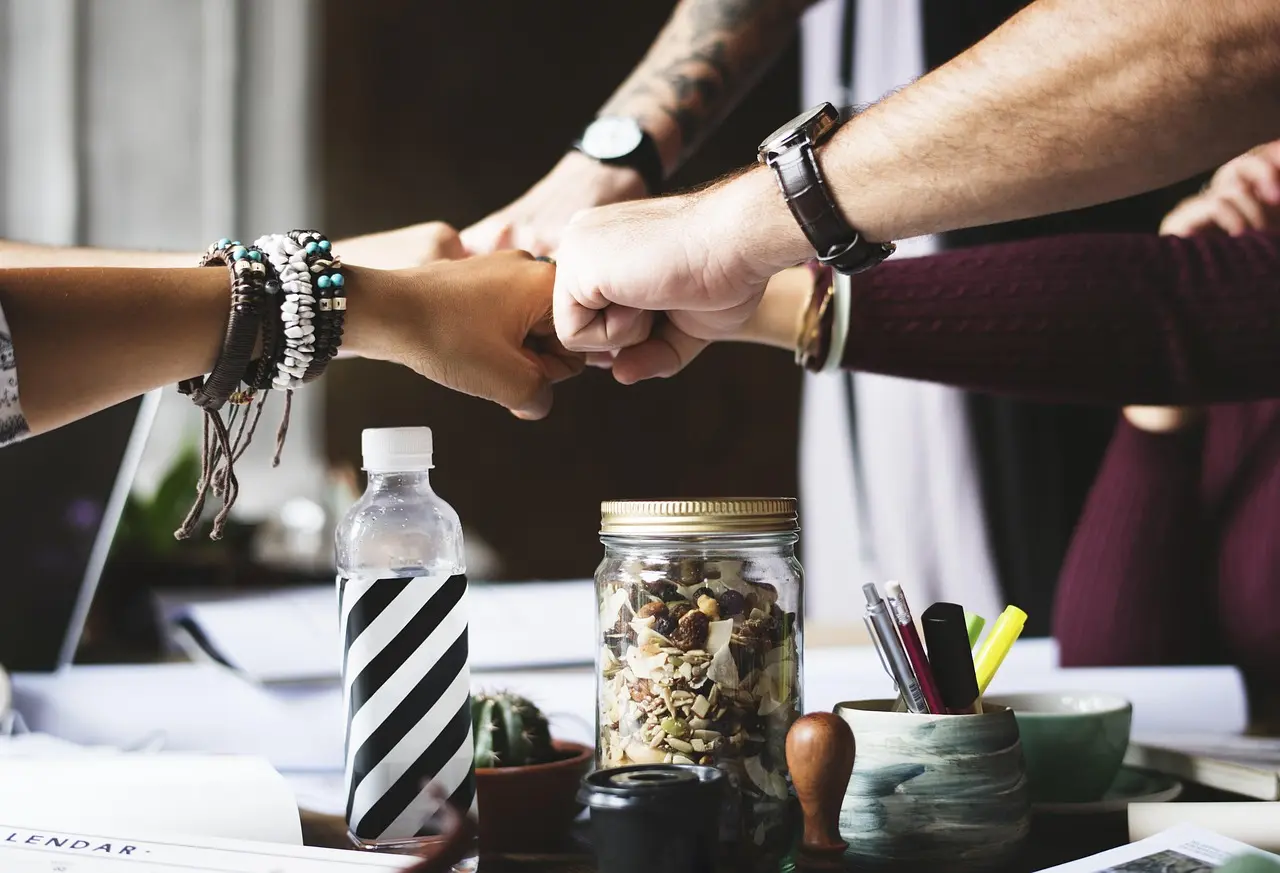 A team in an office joining fists, symbolizing cross-functional execution.